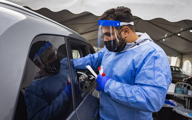 A health worker takes swab samples from Israelis at a drive-thru COVID-19 testing site in Jerusalem on January 2, 2022. (Olivier Fitoussi/Flash90)