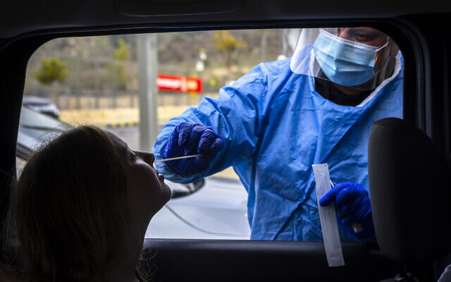 A health worker takes swab samples from Israelis at a drive-thru coronavirus testing complex in Jerusalem, on January 5, 2022. (Olivier Fitoussi/Flash90)