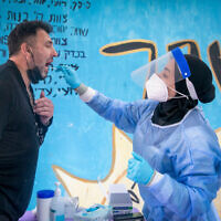 A medical worker takes a COVID-19 rapid antigen test from Israelis, at a testing center in Beit Hashmonai, on January 16, 2022. ( Yossi Aloni/Flash90)