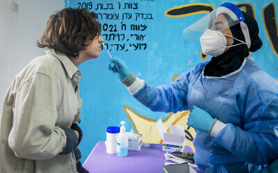 A medical worker takes a swam sample from an Israeli at a testing center in Beit Hashmonai, on January 16, 2022. (Yossi Aloni/Flash90)