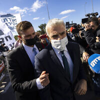 Foreign Affairs Minister Yair Lapid walks through a protest supporting the establishment of a committee of inquiry into the submarine affair, outside the Prime Minister's Office in Jerusalem, January 23, 2022. (Olivier Fitoussi/Flash90)