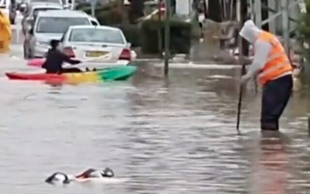 Screen capture from video of a person kayaking down a flooded street in Petah Tikva, January 16, 2022. (Twitter)