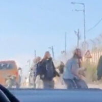 Israeli settlers attack Palestinian cars at a checkpoint in the northern West Bank as an IDF soldier attempts to drive them back on January 26, 2022. (Screen capture: Twitter)