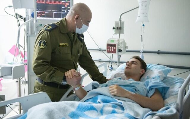 Capt. Ron Birman, right, a naval officer who escaped a helicopter crash, shakes hands with the head of the Israeli Navy, Maj. Gen. David Sa'ar Salame, at Haifa's Rambam Medical Center on January 4, 2022. (Israel Defense Forces)
