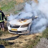 A firefighter douses the flames in an Israeli car after it was allegedly set on fire by Jewish extremists in the West Bank near the outpost of Givat Ronen on Friday, on January 21, 2022. (Courtesy: Yesh Din)