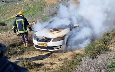 A firefighter douses the flames in an Israeli car after it was allegedly set on fire by Jewish extremists in the West Bank near the outpost of Givat Ronen on January 21, 2022. (Courtesy: Yesh Din)