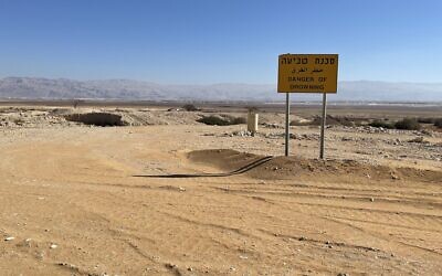 A danger of drowning sign on the way to the Dead Sea Works from where the sea has long since receded, January 20, 2022. (Sue Surkes/Times of Israel)
