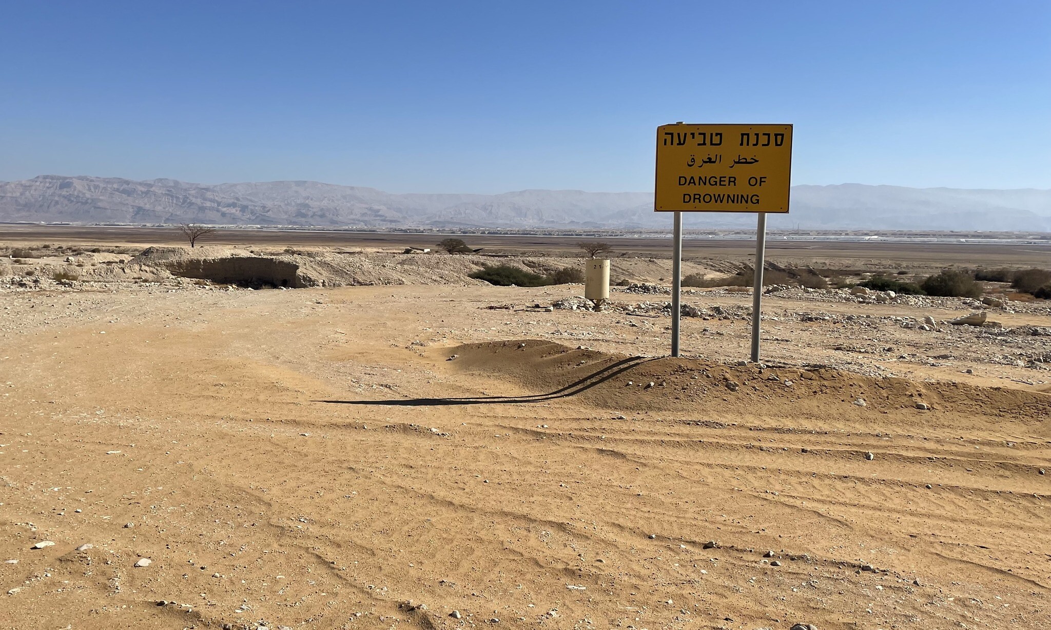 A danger of drowning sign on the way to the Dead Sea Works from where the sea has long since receded, January 20, 2022. (Sue Surkes/Times of Israel)