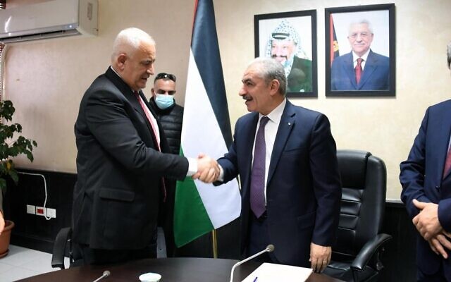 Newly appointed Palestinian Authority Interior Minister Ziad Hab al-Reeh shakes PA premier Mohammad Shtayyeh's hand after formally receiving his portfolio on Sunday, January 2, 2022 (WAFA)