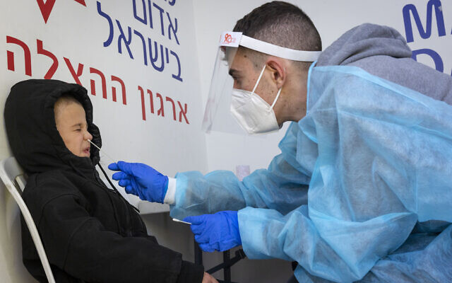 A health worker takes test samples of Israelis at a COVID testing center in Jerusalem on January 9, 2022. (Olivier Fitoussi/Flash90)