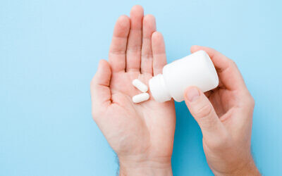 Illustrative: A man spills pills into his hand from a bittle (FotoDuets; iStock by Getty Images)