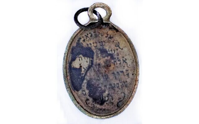 A pendant discovered in the building where victims would undress before being taken to the gas chambers in Sobibor, reading, 'To the faithful king, Hear O Israel, our God is One. Blessed be the name of the glorious king forever and ever.' (Yoram Haimi)