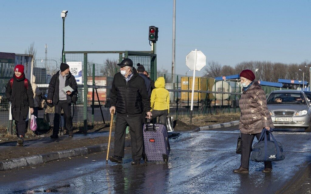 People carry their belongings as they cross the Russian border check point in the region of Avilo-Uspenka, on February 19, 2022. (Andrey BORODULIN / AFP)
