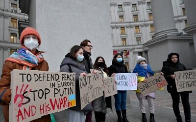 Protesters hold placards demanding sanctions during a rally outside the Ukrainian Ministry of Foreign Affair in Kyiv on February 21, 2022 (Sergei SUPINSKY / AFP)