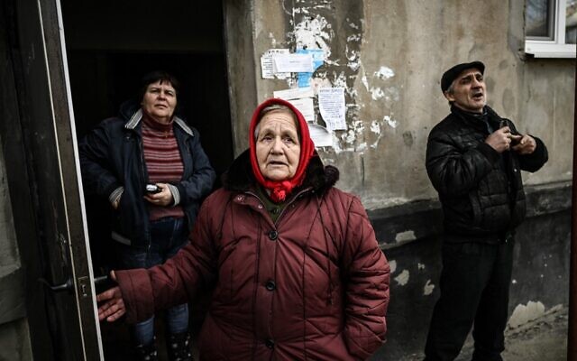 People stand at the door of their building's basement they use as a shelter during bombings in the town of Schastia, near the eastern Ukraine city of Lugansk, on February 22, 2022. (Aris Messinis/AFP)