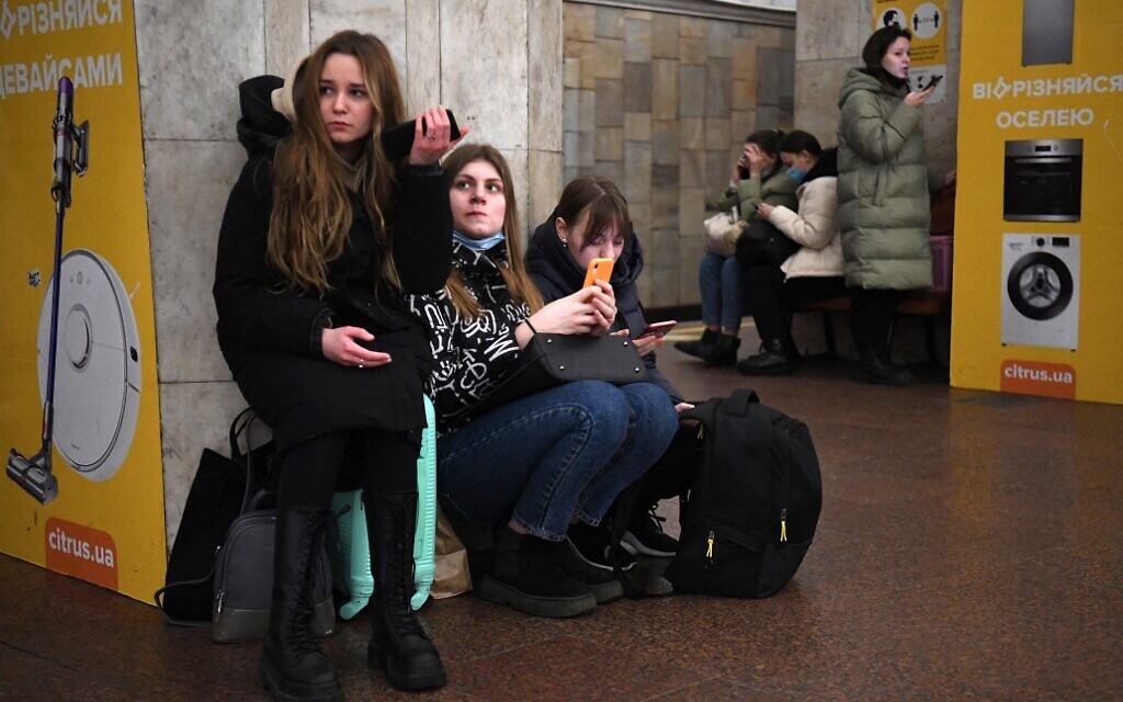 Girls hold their mobile phone as they take refuge in a metro station in Kyiv in the morning of February 24, 2022 (Daniel LEAL / AFP)