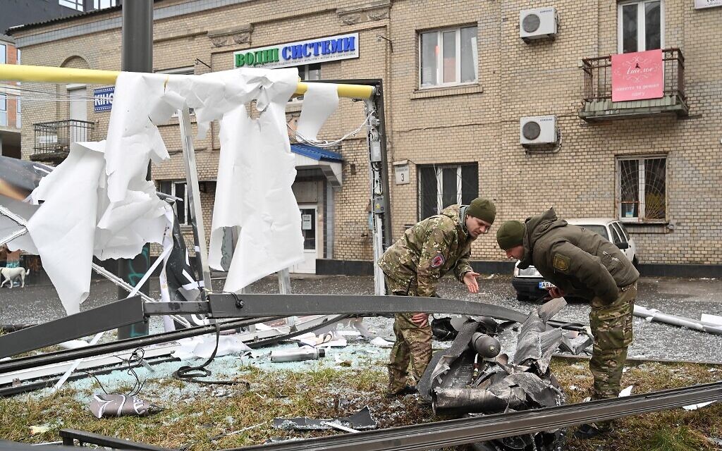 Police and security personnel inspect the remains of a shell in a street in Kyiv on February 24, 2022 (Sergei Supinsky / AFP)