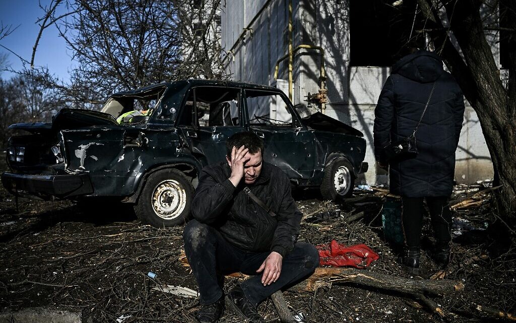 A man sits outside his destroyed building after bombings on the eastern Ukraine town of Chuguiv on February 24, 2022, as Russian armed forces invade Ukraine from several directions (Aris Messinis / AFP)