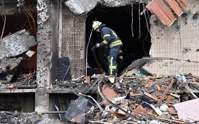 Firefighters work at a damaged residential building at Koshytsa Street, on the outskirts of the Ukrainian capital Kyiv, where a military shell allegedly hit, on February 25, 2022. (GENYA SAVILOV / AFP)