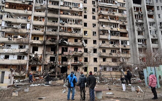 People look at a damaged residential building at Koshytsa Street, on the outskirts of the Ukrainian capital Kyiv, where a military shell allegedly hit, on February 25, 2022. (GENYA SAVILOV / AFP)