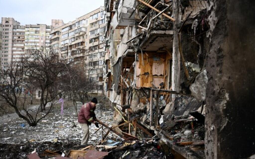 A man clears debris at a damaged residential building at Koshytsa Street, a suburb of the Ukrainian capital Kyiv, where a military shell allegedly hit, on February 25, 2022. (Daniel LEAL/AFP)