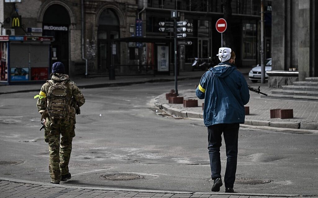 A member of Ukrainian forces, wearing Guy Fawkes mask (Anonymous mask), patrols downtown Kyiv, on February 27, 2022. (Aris Messinis / AFP)