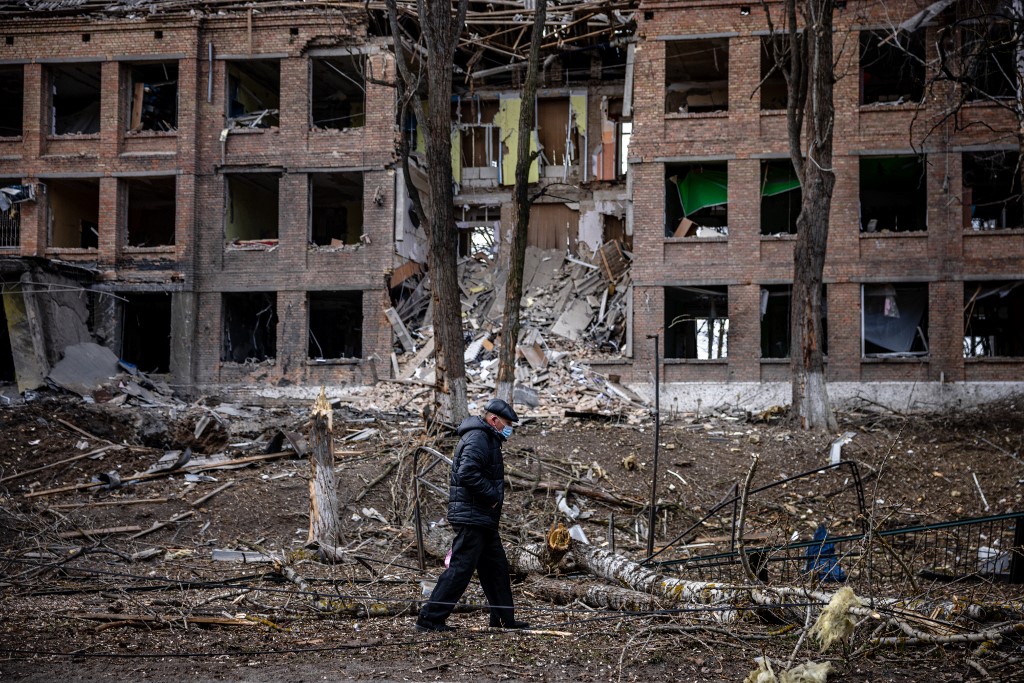 A man walks in front of a destroyed building after a Russian missile attack in the town of Vasylkiv, near Kyiv, on February 27, 2022 (Dimitar Dilkoff/AFP)