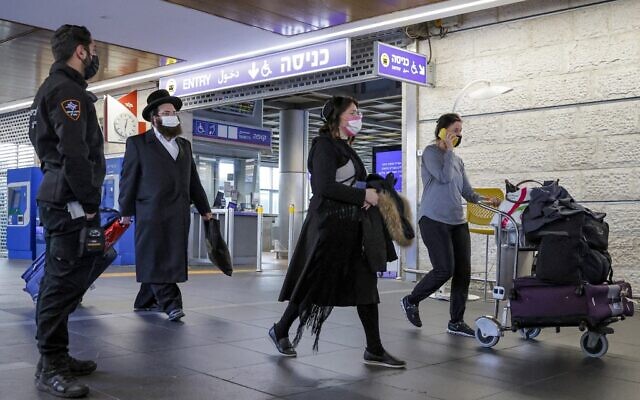 An airport security officer watches as arriving passengers inbound from Kyiv walk with their luggage at Israel's Ben Gurion airport on February 13, 2022. (JACK GUEZ / AFP)