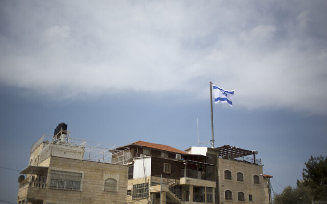 Illustrative: In this March 13, 2019, photo, an Israeli flag flies on a building in East Jerusalem's Mount of Olives. (AP Photo/Ariel Schalit)