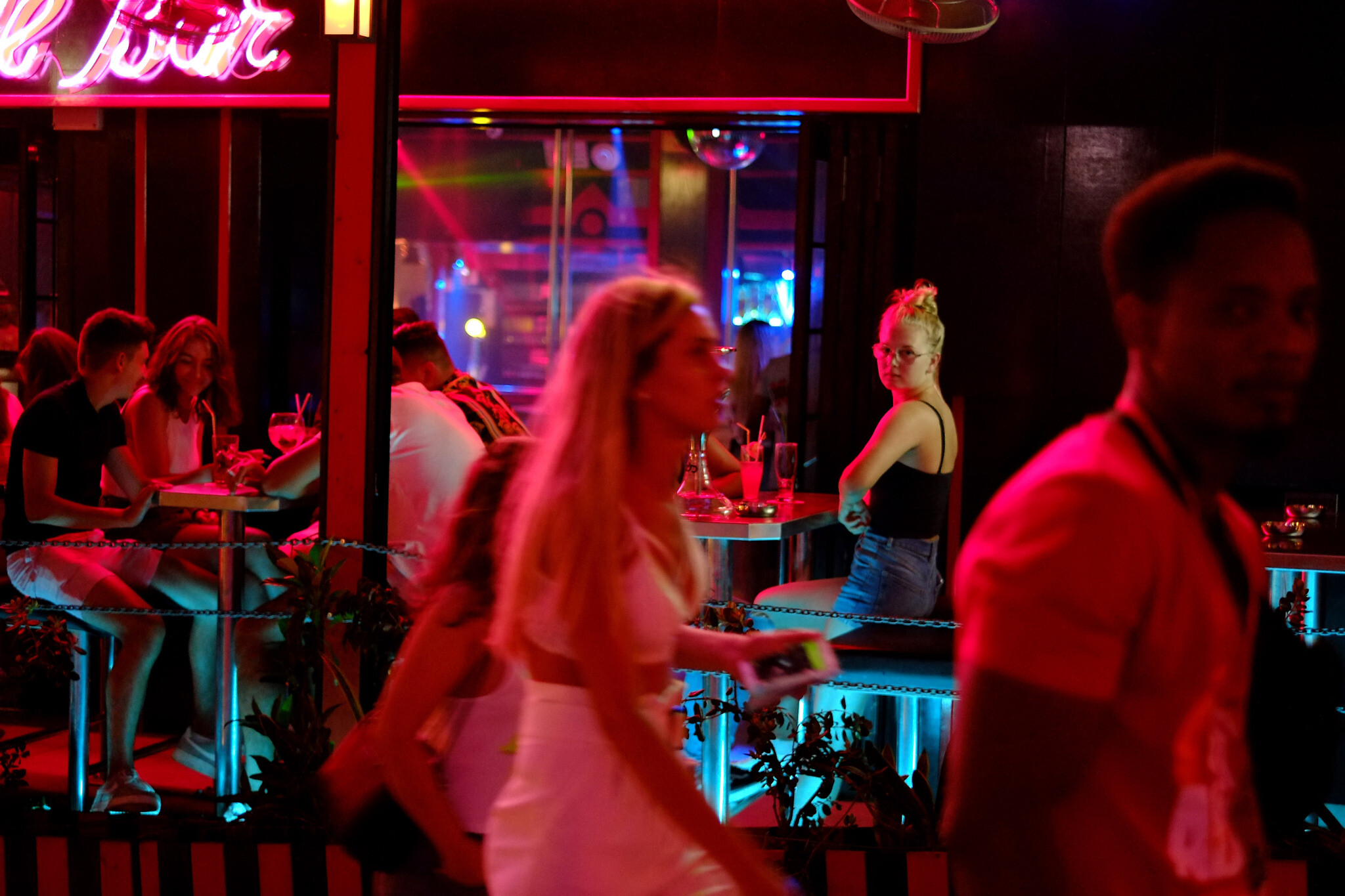 Tourist enjoy their drinks as other walk by a pub in the southeast resort of Ayia Napa in the east Mediterranean island of Cyprus late Wednesday, July 17, 2019.  (AP/Petros Karadjias)