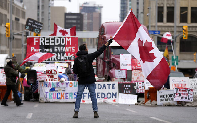 Illustrative: A protester waves a Canadian flag in front of parked vehicles on Rideau Street at a protest against COVID-19 measures that has grown into a broader anti-government protest, in Ottawa, Ontario, Friday, Feb. 11, 2022. (Justin Tang/The Canadian Press via AP)