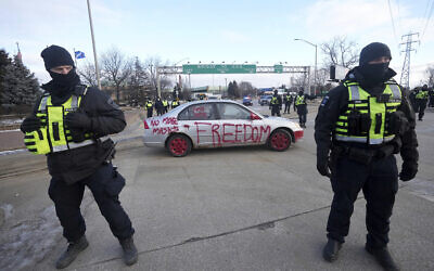 Police look on as a protest vehicle leaves a demonstration which has blocked traffic across the Ambassador Bridge by protesters against COVID-19 restrictions in Windsor, Ontario, Canada Feb. 12, 2022. (Nathan Denette/The Canadian Press via AP)