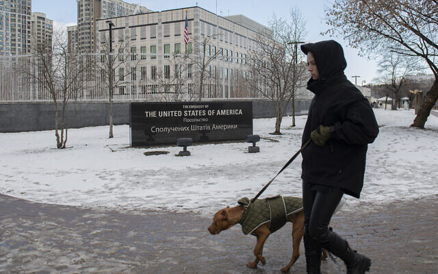 A man walks with his dog in front of the US Embassy in Kyiv, Ukraine, February 12, 2022. (AP Photo/Andrew Kravchenko)