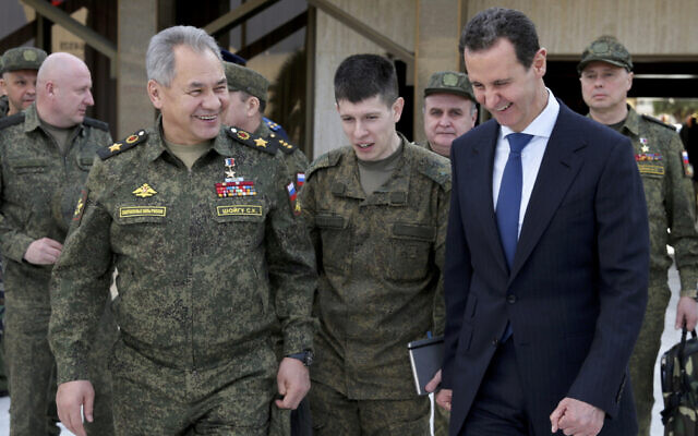 In this photo taken from video provided by the Russian Defense Ministry Press Service on February 15, 2022, Russian Russian Defense Minister Sergei Shoigu, left, and Syrian President Bashar Assad, right, smile during their meeting in Damascus, Syria. (Russian Defense Ministry Press Service via AP)