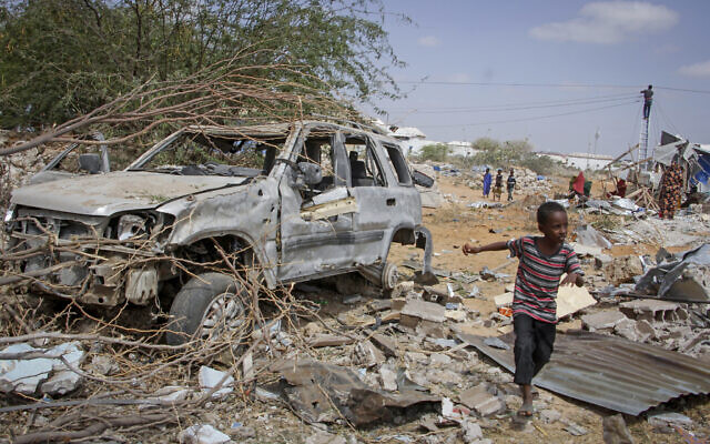 A young boy runs past the wreckage of a vehicle destroyed in an attack on police and checkpoints on the outskirts of the capital Mogadishu, Somalia Wednesday, Feb. 16, 2022. (AP Photo/Farah Abdi Warsameh)