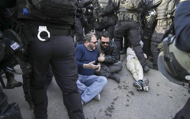 Israeli riot police officers scuffle with protesters during a protest to show solidarity with Palestinian residents of East Jerusalem's Sheikh Jarrah neighborhood, February 18, 2022. Pictured on the ground in a blue sweater is Joint List MK Ofir Cassif. (AP Photo/Mahmoud Illean)