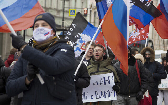 Pro-Kremlin activists and students rally with Russian and Donetsk People republic flags and a poster that reads: 'Donetsk Luhansk People republics we are together' celebrating the recognition of rebel-controlled regions in Donbas, at the Palace Square in St. Petersburg, Russia, on Wednesday, February 23, 2022. (AP Photo/Ivan Petrov)