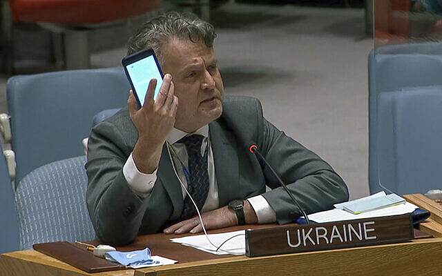 In this image from UNTV video, Ukraine's Ambassador to the United Nations Sergiy Kyslytsya, holds up a phone as he speaks an emergency meeting of the UN Security Council  at UN headquarters, Feb. 23, 2022. (UNTV via AP)