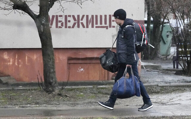A man walks past a writing 'Bomb shelter' on the wall in Mariupol, Ukraine, Feb. 24, 2022 (AP Photo/Sergei Grits)