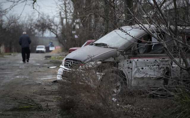 A man walks past a damaged vehicle and debris following Russian shelling in Mariupol, Ukraine, on Thursday, February 24, 2022. (AP Photo/Sergei Grits)