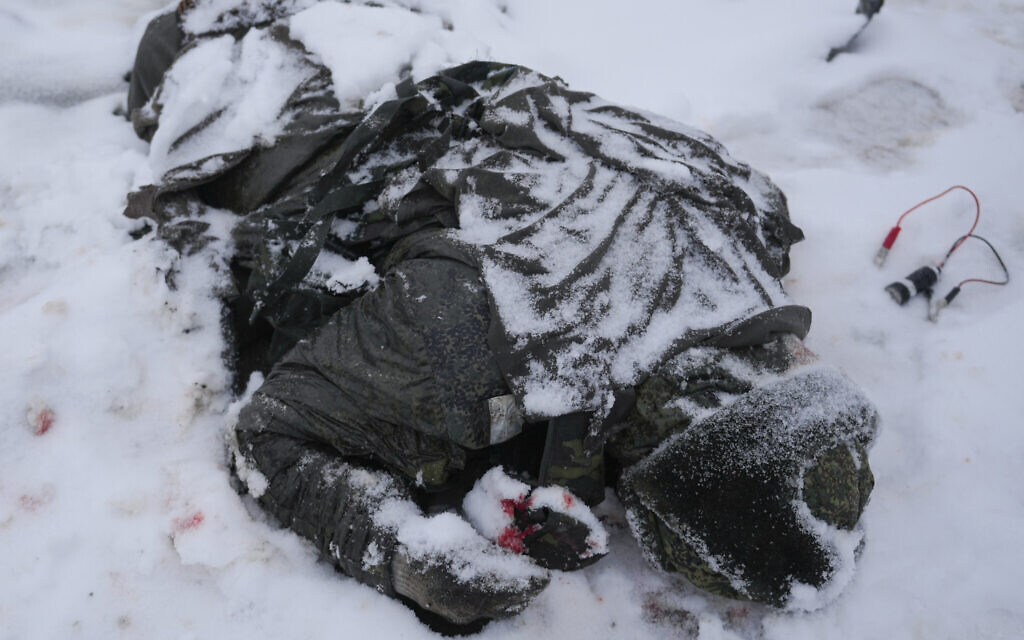 The body of a serviceman is coated in snow next to a destroyed Russian military multiple rocket launcher vehicle on the outskirts of Kharkiv, Ukraine, Friday, Feb. 25, 2022.  (AP Photo/Vadim Ghirda)