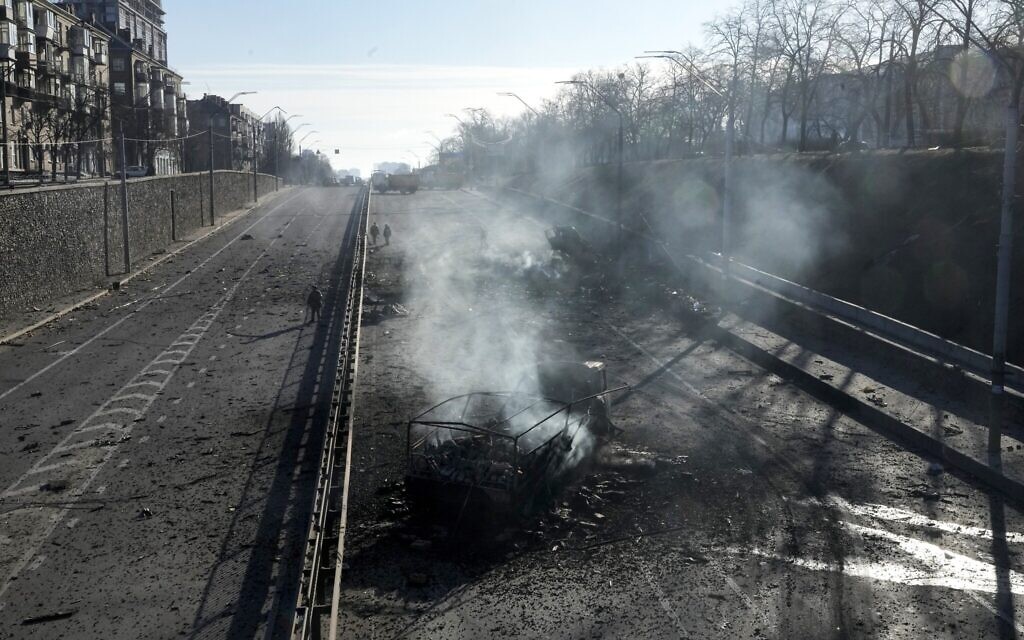 Ukrainian soldiers walk around debris of burning military trucks in a street in Kyiv, Ukraine, February 26, 2022. (AP Photo/Efrem Lukatsky)