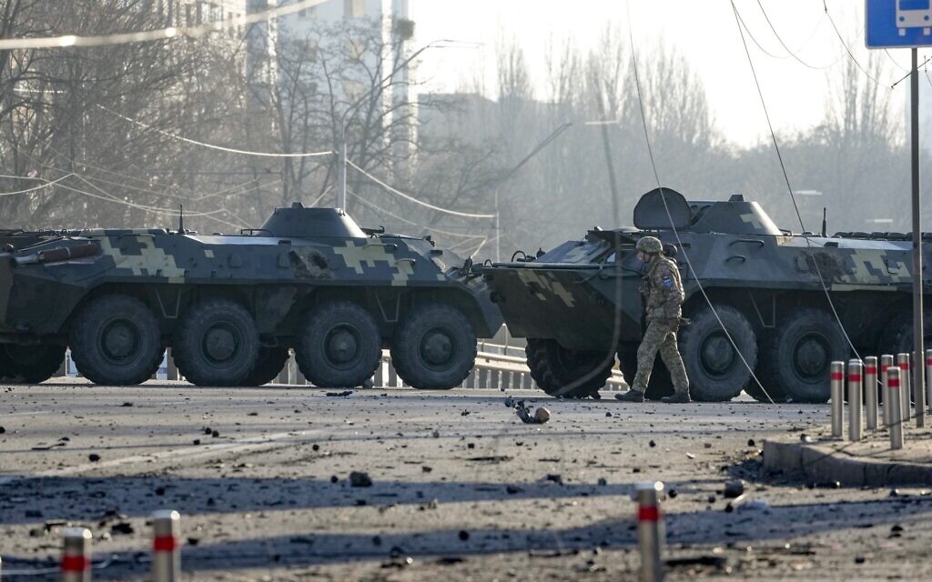 A soldier walks along Ukrainian armored vehicles blocking a street in Kyiv, Ukraine, on Saturday, February 26, 2022. (AP/Efrem Lukatsky)