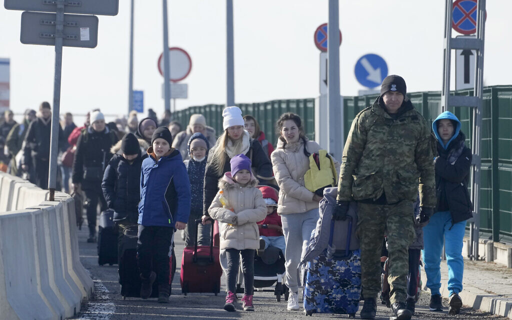 A Polish border guard assists refugees from Ukraine as they arrive to Poland at the Korczowa border crossing, Poland, on Saturday, February 26, 2022. (AP/Czarek Sokolowski)