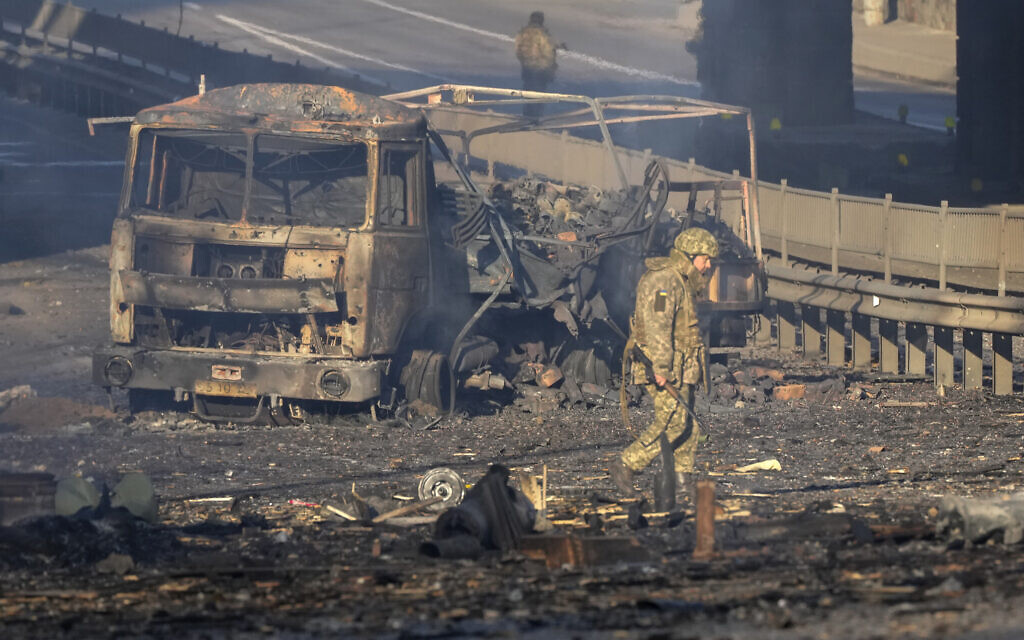 A Ukrainian soldier walks past debris of a burning military truck, on a street in Kyiv, Ukraine, Feb. 26, 2022. (AP Photo/Efrem Lukatsky)