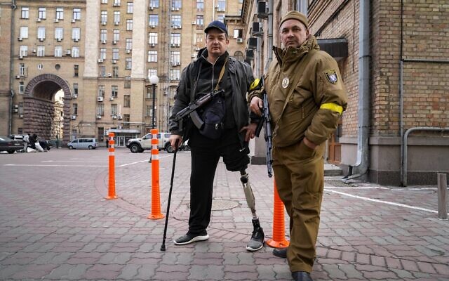 Armed civil defense men pose for a photo while patrolling an empty street due to curfew in Kyiv, Ukraine, Feb. 27, 2022 (AP Photo/Efrem Lukatsky)
