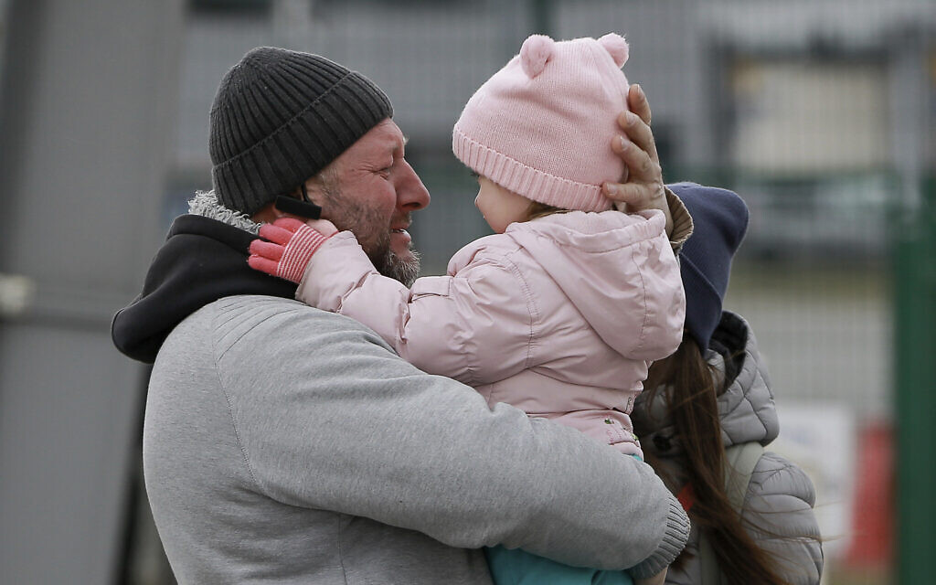 A father hugs his daughter as the family reunite after fleeing conflict in Ukraine, at the Medyka border crossing, in Poland, Feb. 27, 2022  (AP Photo/Visar Kryeziu)