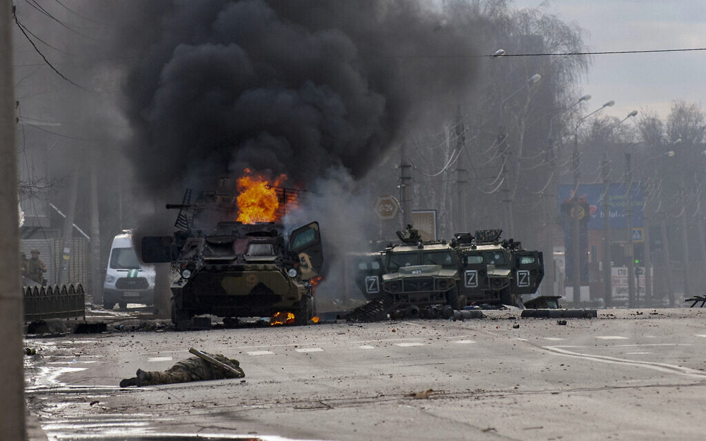 A Russian armored personnel carrier burns amid damaged and abandoned light utility vehicles after fighting in Kharkiv, Ukraine, on February 27, 2022. (AP Photo/Marienko Andrew)
