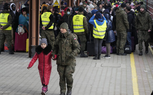 A child is accompanied by a soldier as refugees from Ukraine arrive to the railway station in Przemysl, Poland, Feb. 27, 2022. (Czarek Sokolowski/AP)