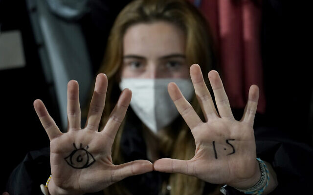A youngster, with an eye drawn on her hand to show she is watching and 1.5 for countries to keep warming below 1.5 degrees Celsius, takes part in a Fridays for Future climate protest inside a plenary corridor at the SEC (Scottish Event Campus) venue for the COP26 U.N. Climate Summit, in Glasgow, Scotland, Nov. 10, 2021. (Alberto Pezzali/AP)